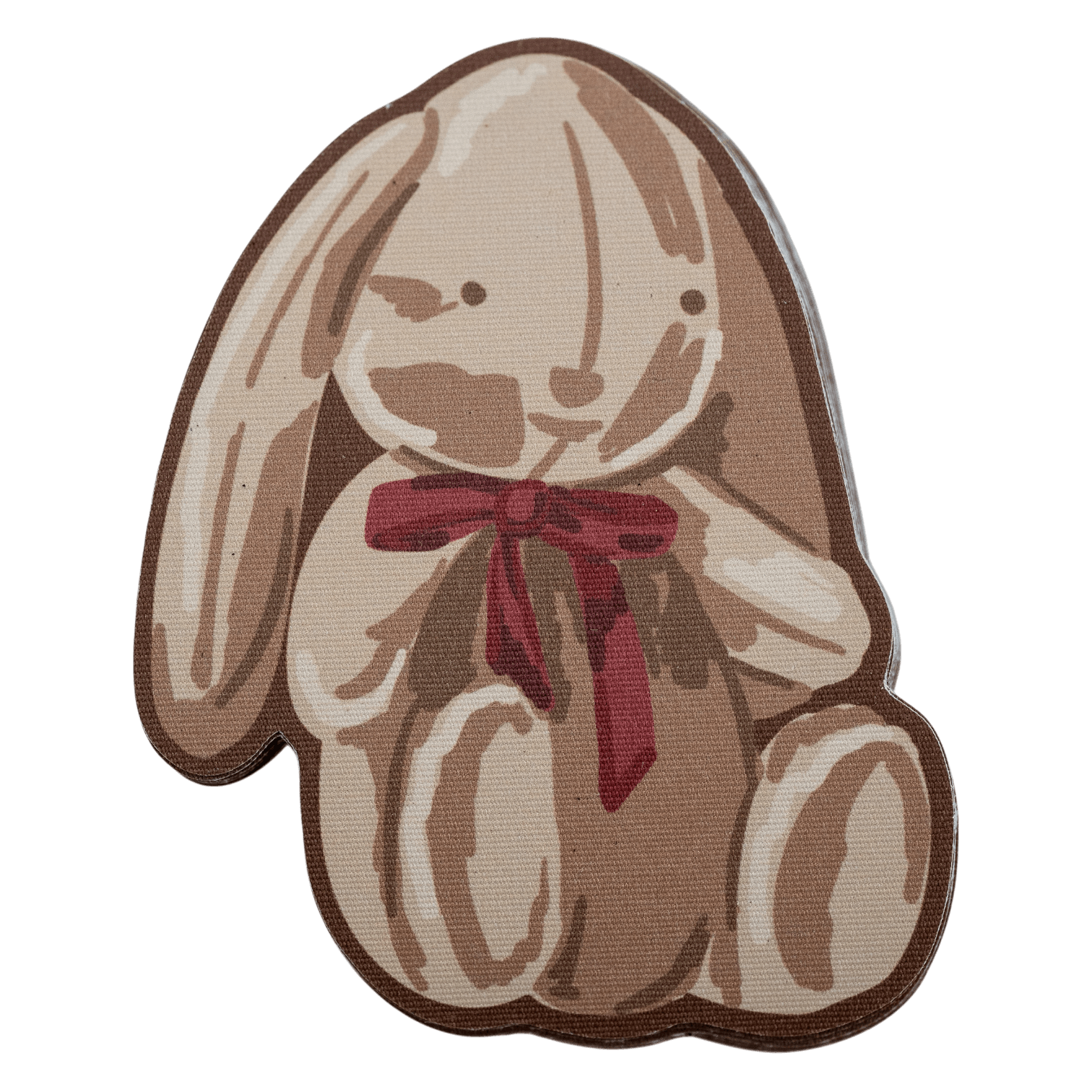 Fabric sticker shaped like a sitting bunny with long floppy ears and a red bow, in soft brown and cream tones
